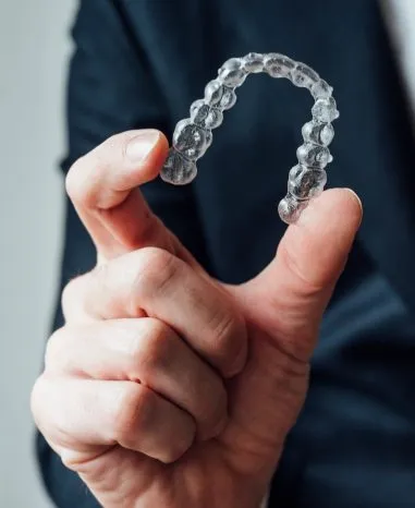 Clear aligner held between finger and thumb